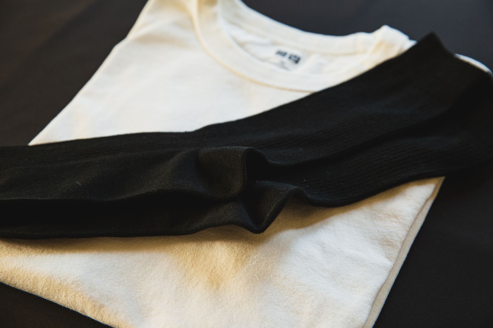 Remeras blancas de algodón dobladas vistas desde arriba con un par de medias negras