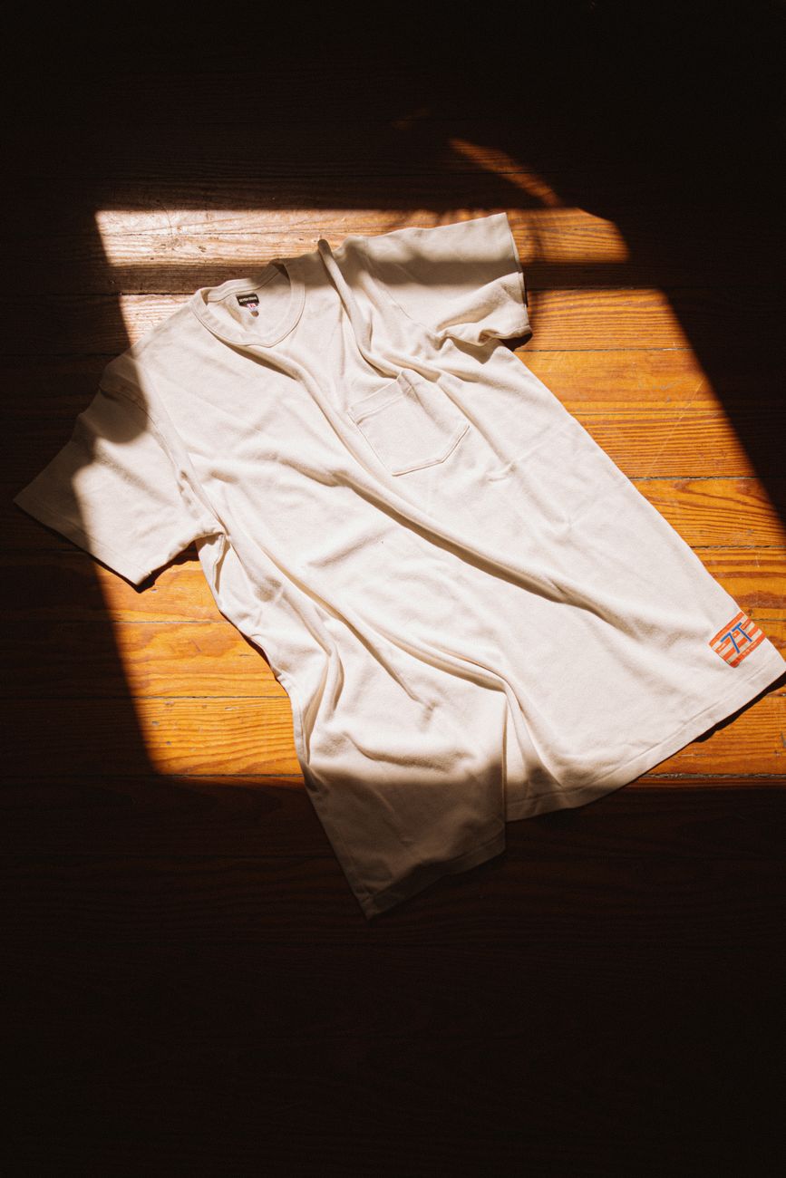 Remera blanca minimalista extendida al sol sobre madera